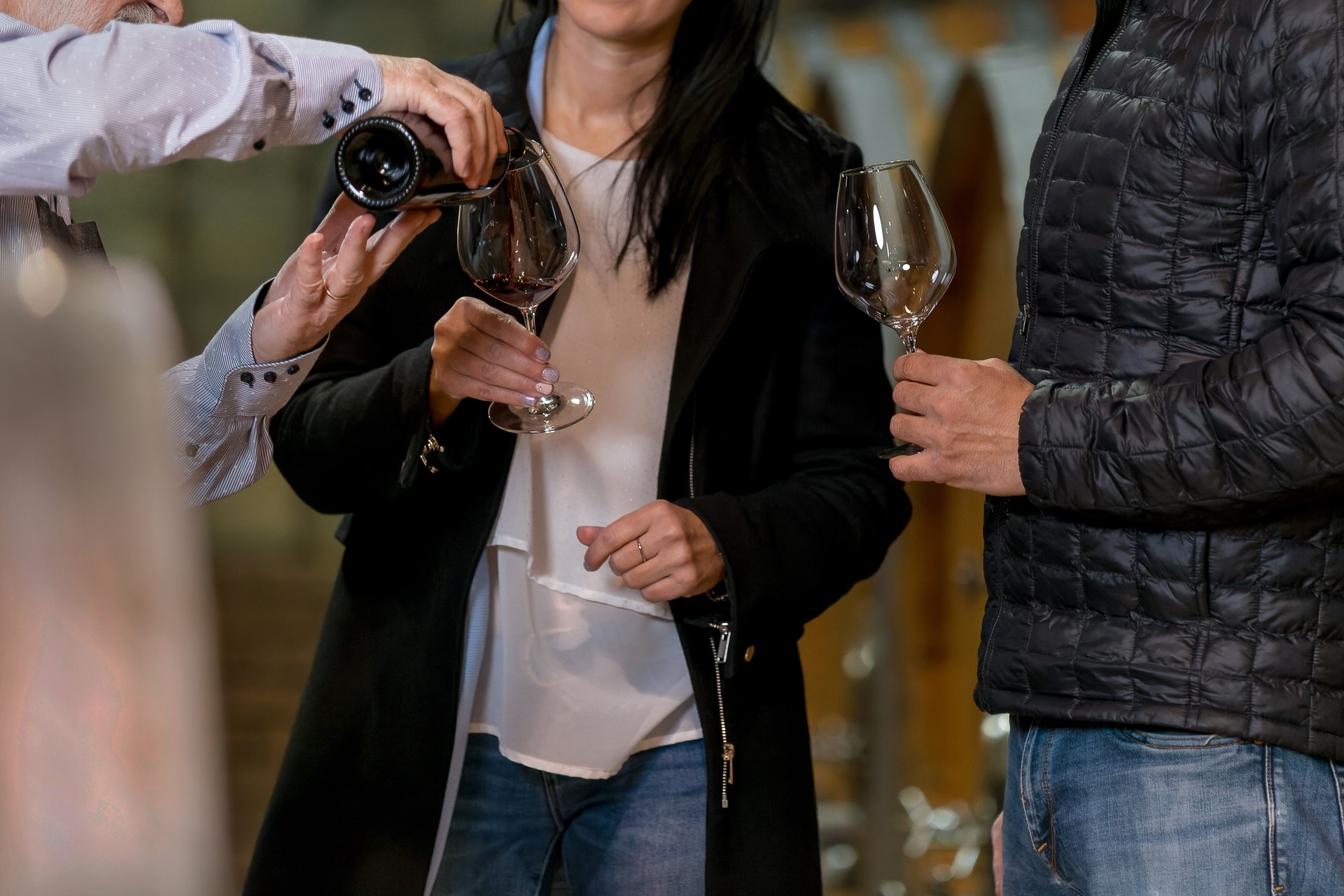 Couple having a private tasting with a wine producer in a wine cellar