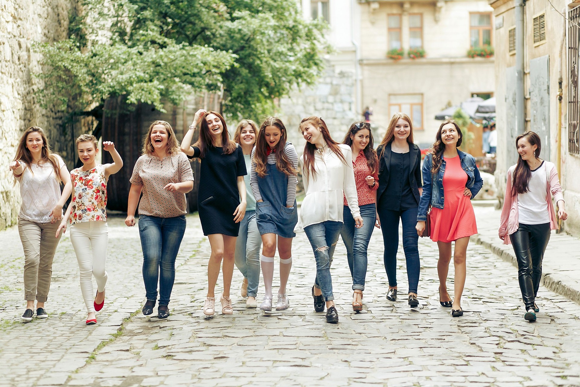 Group of many happy women walking having fun on background of old european city street, celebrating friendship concept, moments of happiness